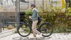 Ein Mann läuft mit seinem Fahrrad und Helm am Bahnhof entlang