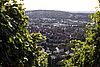 Panoramaansicht einer Stadt mit roten Dächern und grünen Hügeln im Hintergrund.