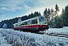 Historische Bahn in weiß und rot fährt durch eine Winterlandschaft.