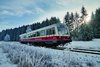 Historische Bahn in weiß und rot fährt durch eine Winterlandschaft. 