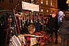 Stand mit der Aufschrift Schabernack auf einem Weihnachtsmarkt mit vielen Glocken. Davor steht ein Mann mit rot-schwarz-karierter Kappe und andere Besuchende.