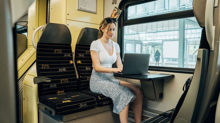 Eine Frau arbeitet während einer Bahnfahrt an ihrem Laptop
