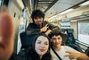 Drei Jugendliche sitzen zusammen in der Bahn und machen ein Selfie. Die beiden Jungen zweigen ein Peace-Zeichen, das Mädchen hält das Smartphone.