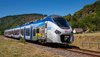 Ein SNCF Zug fährt durch eine grüne Landschaft.