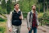 Zwei junge Männer in Wanderkleidung wandern durch den Wald.