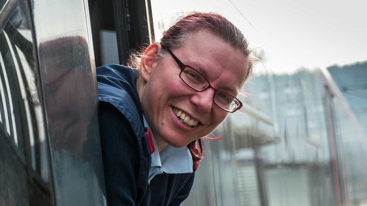 Lokführerin mit Brille schaut aus Zugfenster.