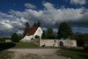 Das verlassene Dorf Gruorn mit Friedhof und Kirche vor einem bewölkten Himmel