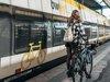 Junge Frau geht mit Fahrrad den Bahnsteig entlang. 