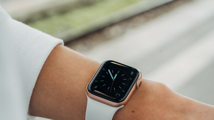 Nahaufnahme einer Uhr am Handgelenk, im Hintergrund sieht man das Bahngleis