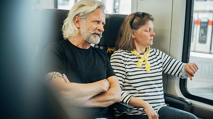 Ein Mann und eine Frau sitzen nebeneinander in der Bahn.