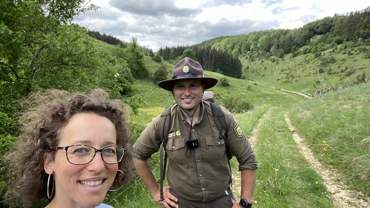Frau steht mit einem Ranger in der Natur.