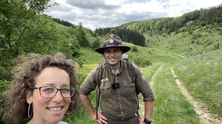 Frau steht mit einem Ranger in der Natur.