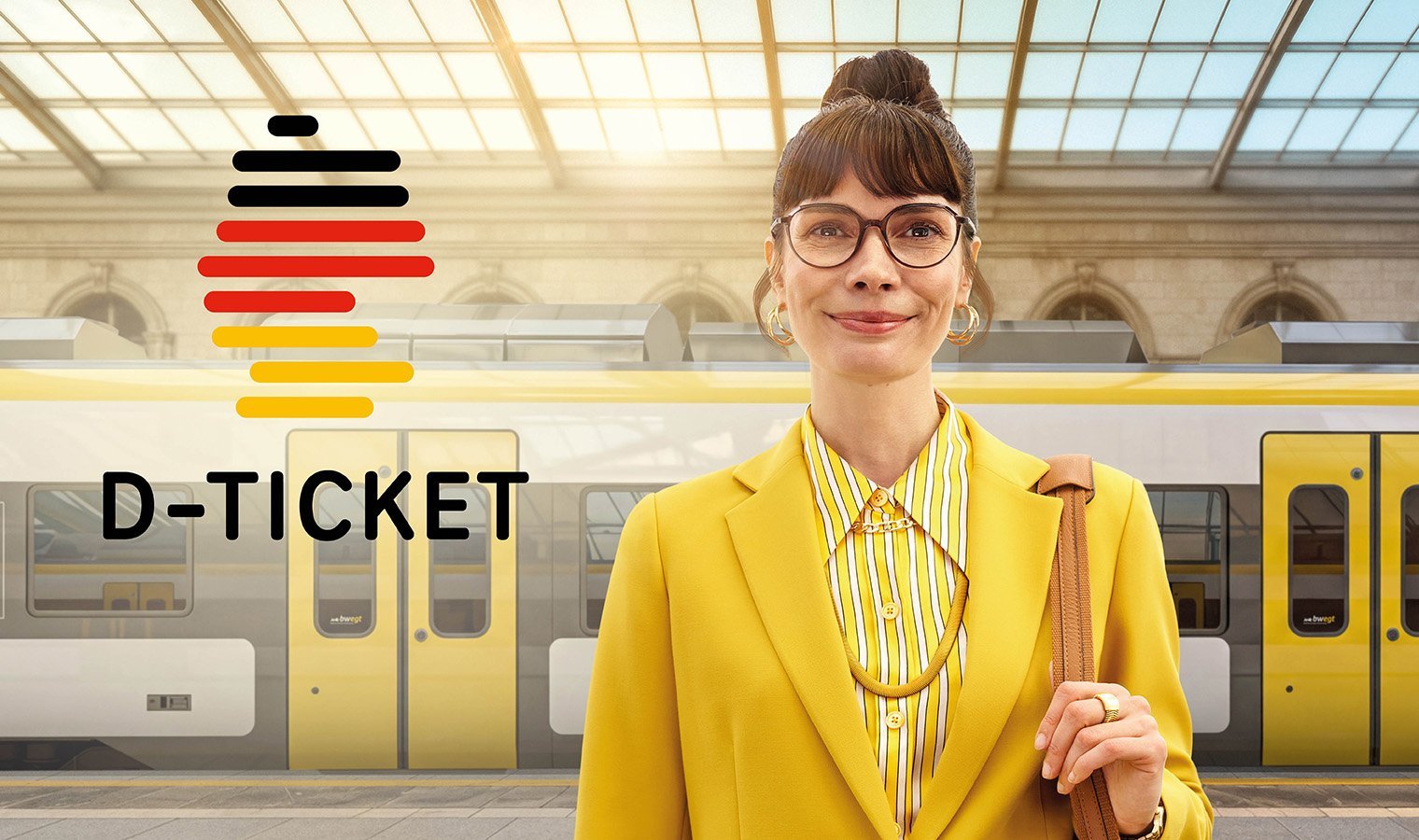 Eine Frau in gelber Kleidung steht an einem Bahnhof. Hinter ihr fährt ein bwegt-Zug vorbei.