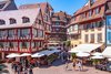Fachwerkhäuser in Colmar, mit Sonnenschirmen und Leuten im Vordergrund
