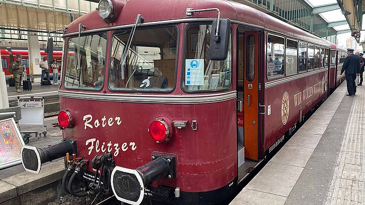 Rote altmodische Bahn steht am Bahnhof.