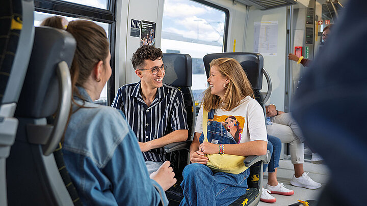 Junge Menschen sitzen im bwegt-Zug zusammen und unterhalten sich