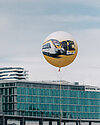 Ein gelber bwegt-Ballon mit einem Zug- und Busmotiv