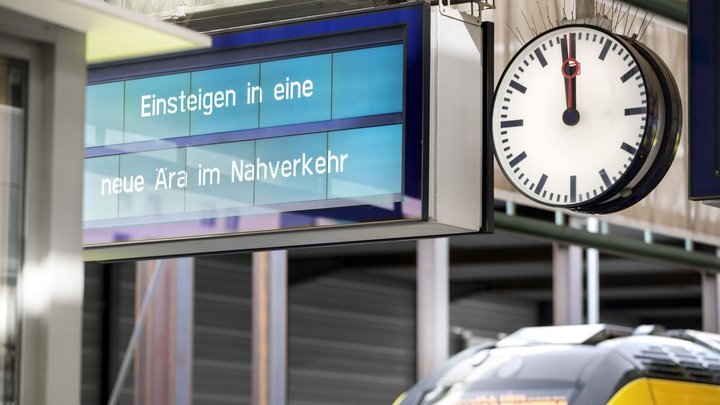 Auf einer Anzeige im Bahnhof steht "Einsteigen in eine neue Ära im Nahverkehr"