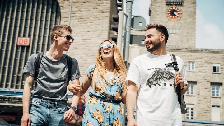 Drei junge Leute lachen am Bahnhof in Stuttgart.