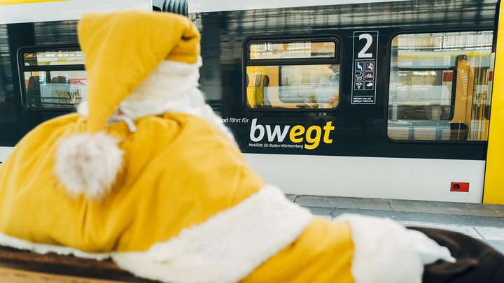 Auf einer Bank am Bahngleis wartet ein gelb verkleideter Weihnachtsmann