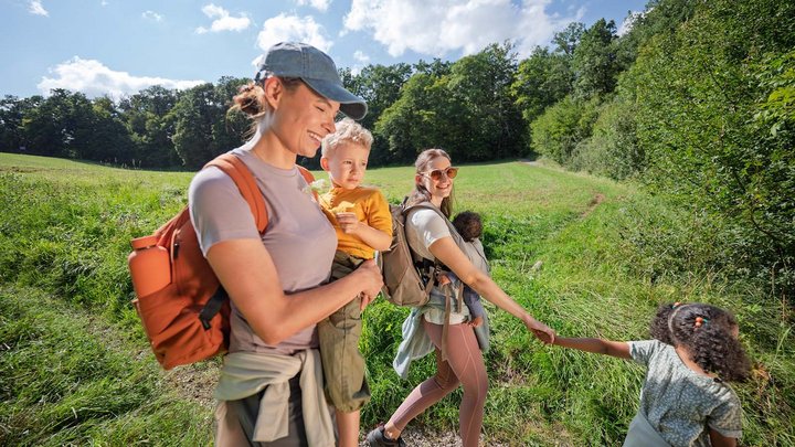 Eine junge Familie mit Kindern wandert über eine große Wiese