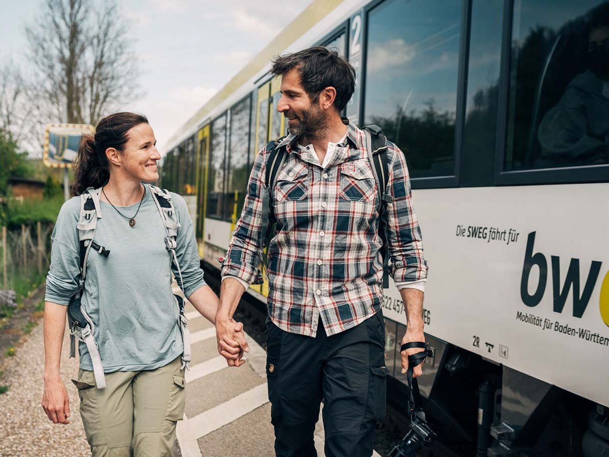 Paar läuft Hand in Hand den Bahnsteig entlang.