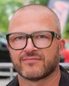 Mann mit Brille blickt in die Kamera.