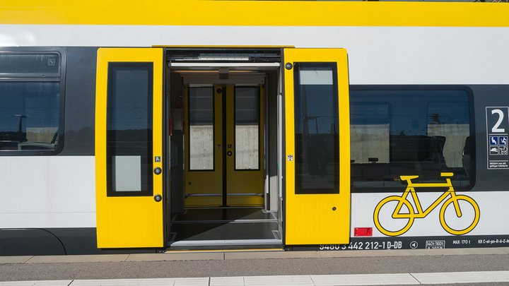 An einem Bahnhof steht eine Zugtür weit offen