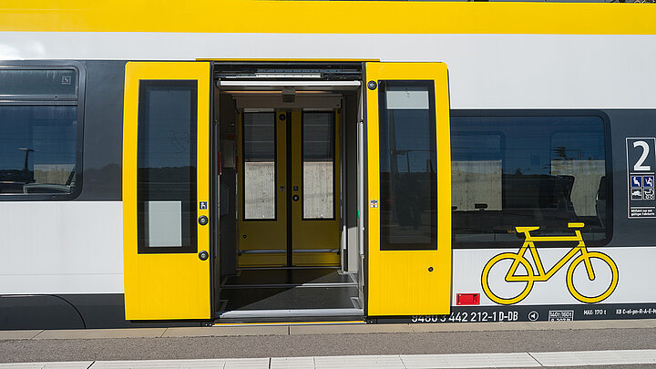 An einem Bahnhof steht eine Zugtür weit offen