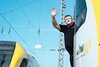 Lokführer lehnt sich aus dem Führerstand des Zuges und winkt mit erhobener Hand.