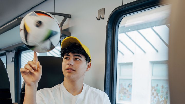 Junge balanciert Ball auf dem Finger