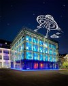 Ein in blauer Farbe leuchtendes Kunstmuseum in Karlsruhe mit einem gezeichneten Ufo darin.