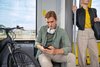 Ein junger Mann schaut während der Bahnfahrt auf sein Smartphone
