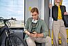 Ein junger Mann schaut während der Bahnfahrt auf sein Smartphone
