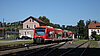 Ein roter Zug vor einer ländlichen Wohnsiedlung