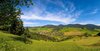 Grün erstrahlende Landschaft mit Blick auf ein Dorf in der Ferne.
