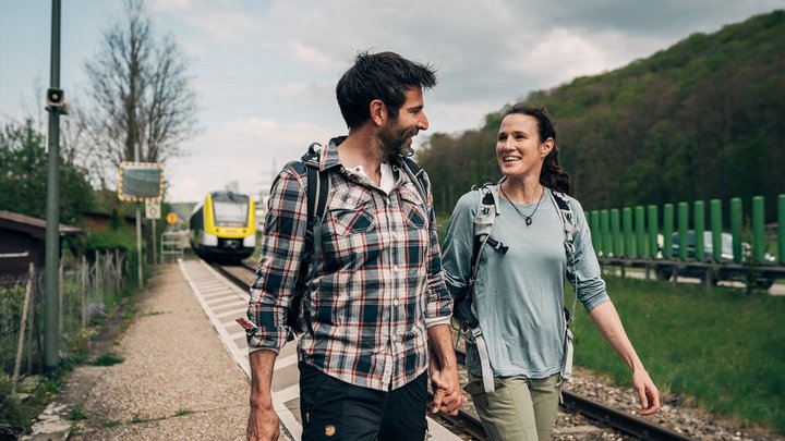 Paar geht Hand in Hand am Bahngleis entlang.