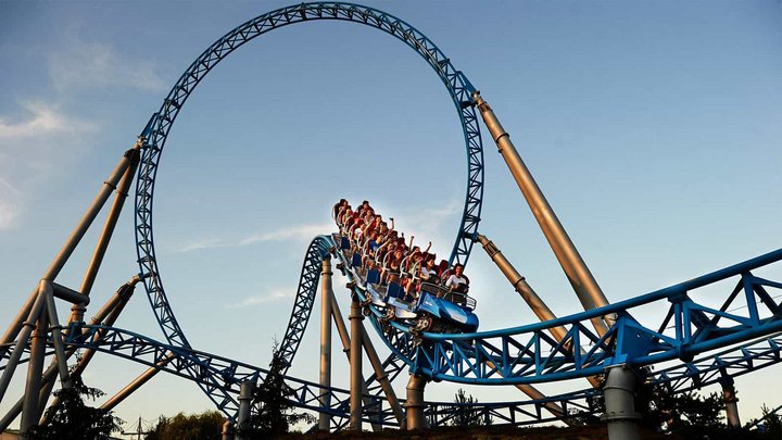 Achterbahn mit Looping vor blauem Himmel.