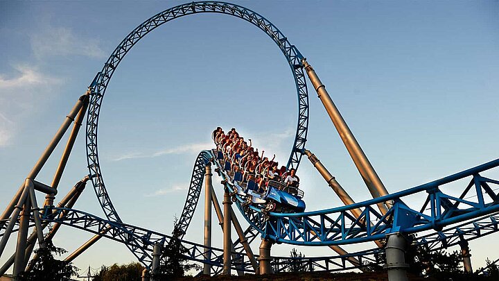Achterbahn mit Looping vor blauem Himmel.