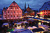 Inmitten eines Klosterhofs mit Fachwerkhäusern sind mehrere Stände eines Weihnachtsmarktes aufgebaut. Es ist dunkel und die Lichter der Stände sorgen für eine gemütliche Stimmung.