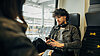 Ein junger Mann sitzt während der Bahnfahrt an seinem Handy.
