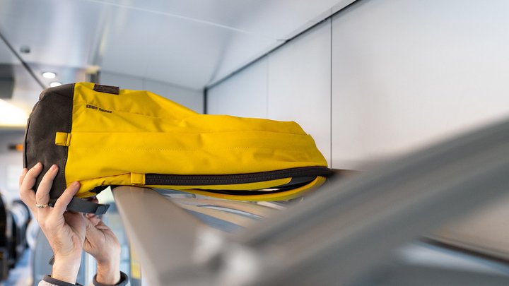 Ein gelber Rucksack wird in einem Zug verstaut
