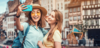 Zwei junge Frauen machen ein Selfie in einer französischen Altstadt
