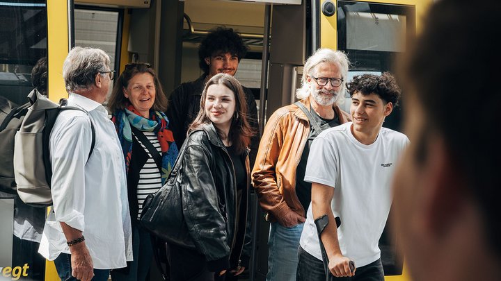 Eine Gruppe an Personen verlässt glücklich die Bahn.