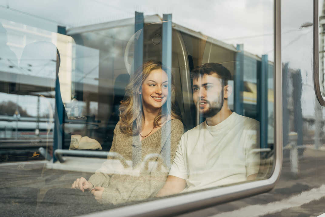 Ein junges Paar sitzt am Fenster im Zug