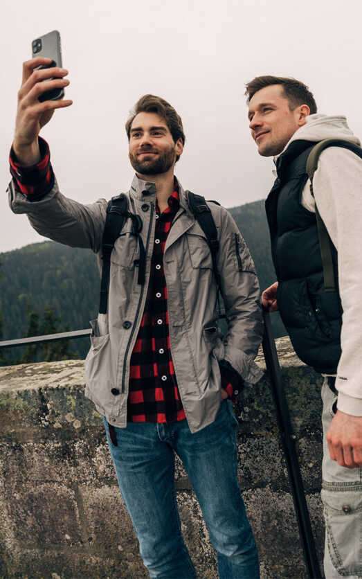 Zwei junge Männer machen ein Foto mit ihrem Smartphone.