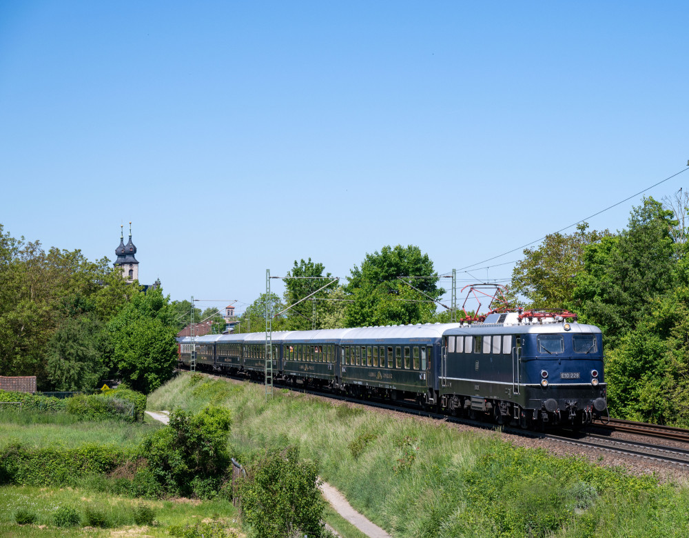 Der blaue Classic Courier Zug fährt durch eine grüne Landschaft