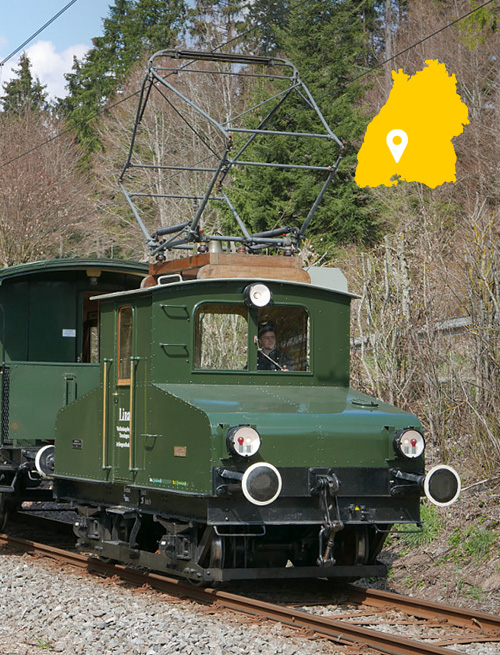 Ein grüner historischer Zug fährt durch eine Landschaft