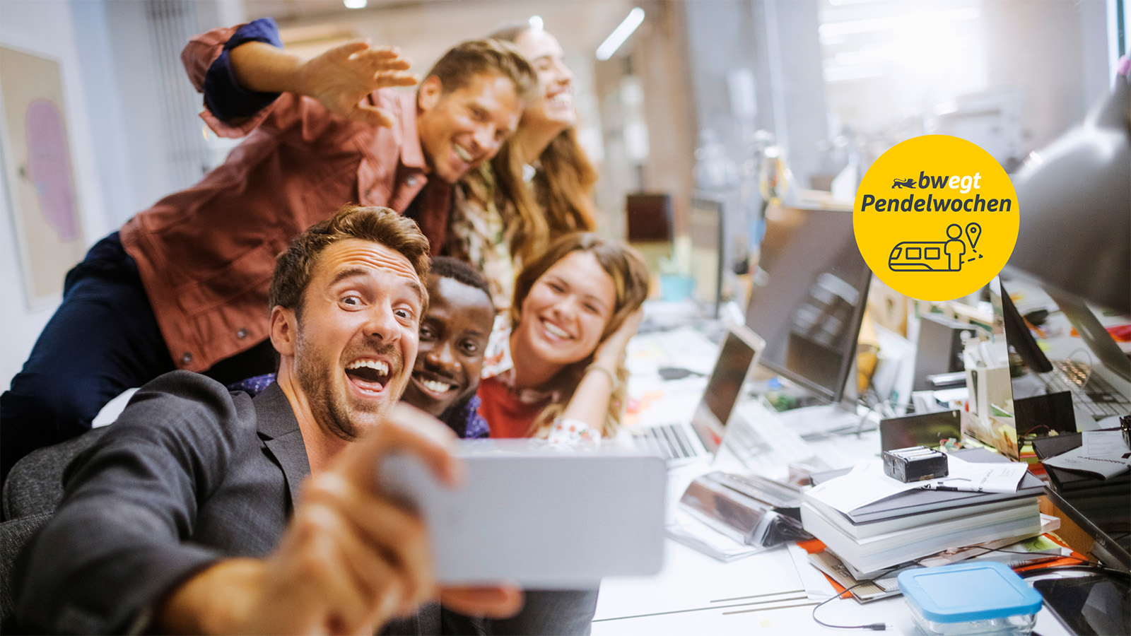 Eine Gruppe Arbeitskolleg:innen macht ein Gruppenbild am Arbeitsplatz
