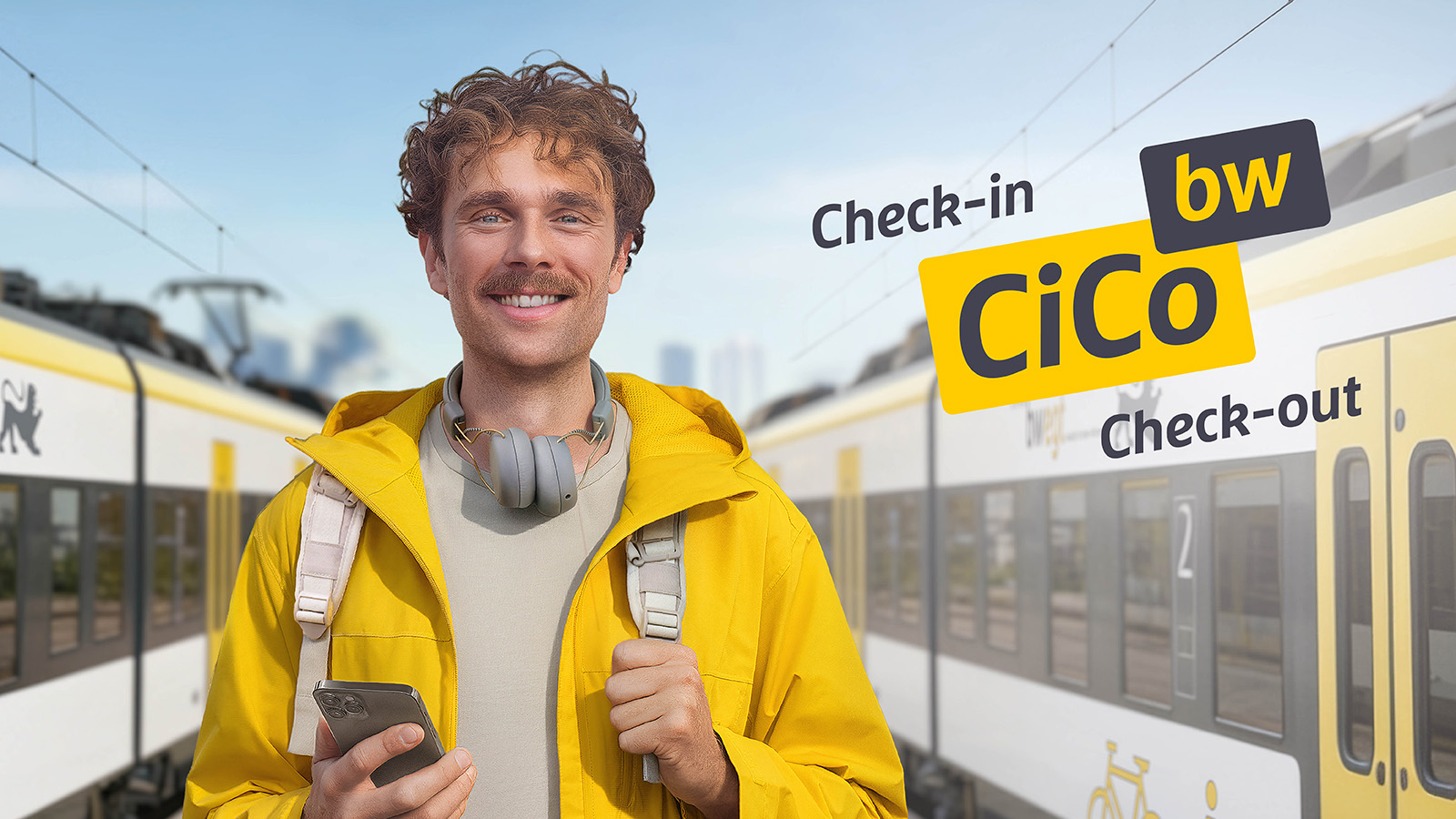 Ein Mann in gelber Kleidung steht mit seinem Handy am Bahnhof. Links und rechts von ihm steht jeweils ein bwegt-Zug.